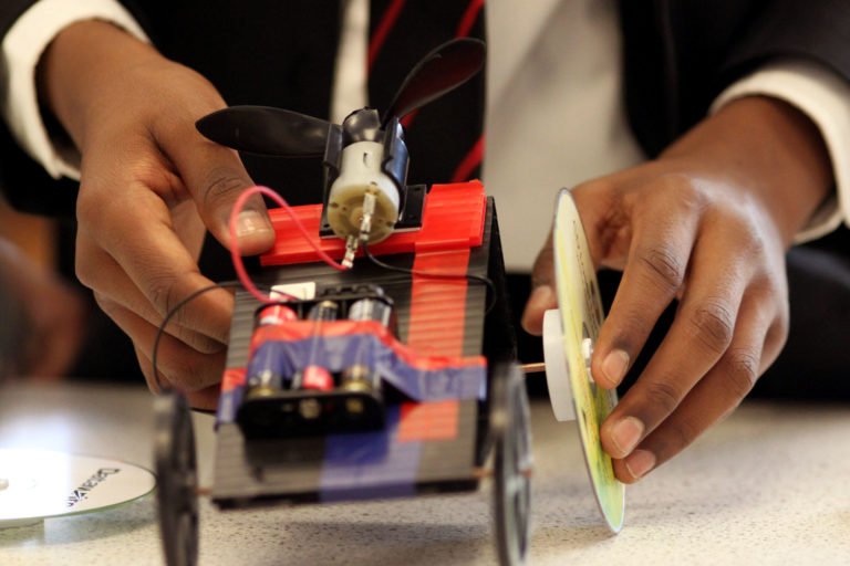Hands building a fan-powered car
