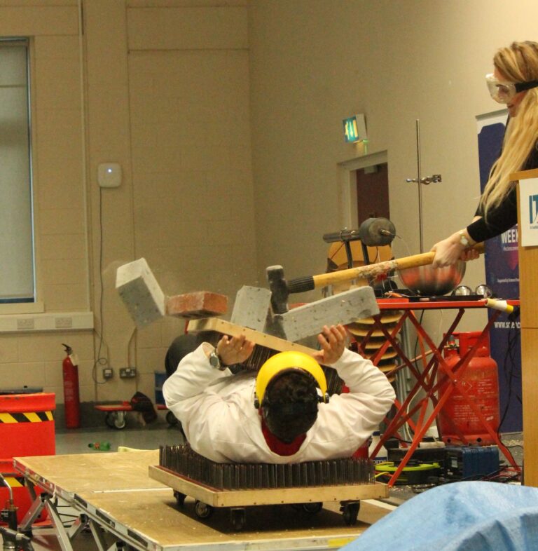 Peter being smacked with a sledge hammer while laying on a bed of nails